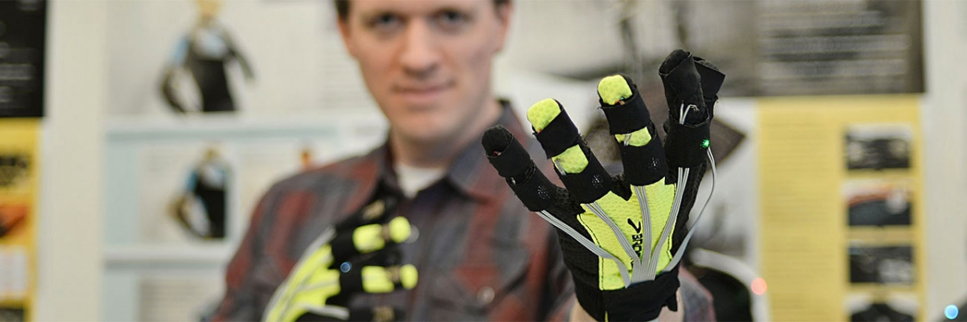 An industrial design student researching wearable technologies wears yellow and black haptic gloves.