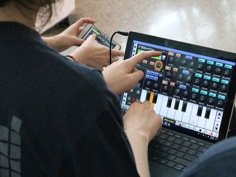 Laptop Orchestra students use an app on a tablet to play music.
