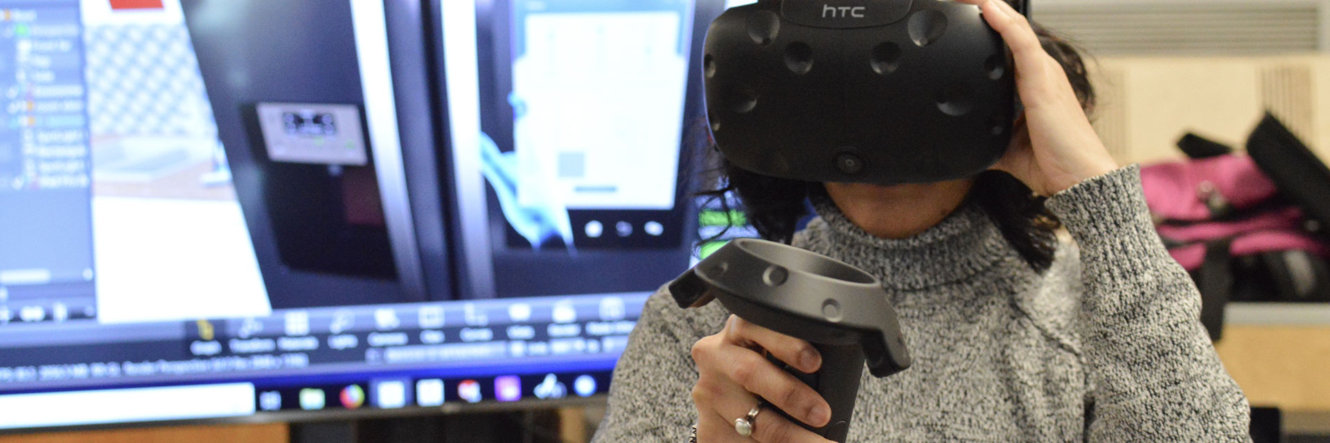 An industrial design student wears a VR headset and uses a joystick.