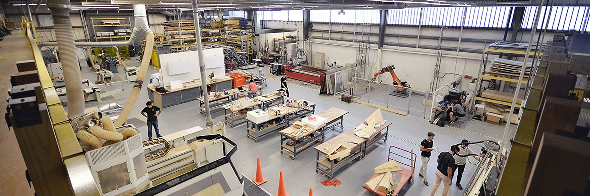 A top-down view of several students working in the Digital Fabrication Lab, showing several work tables, CNC machines, and a Kuka robot.