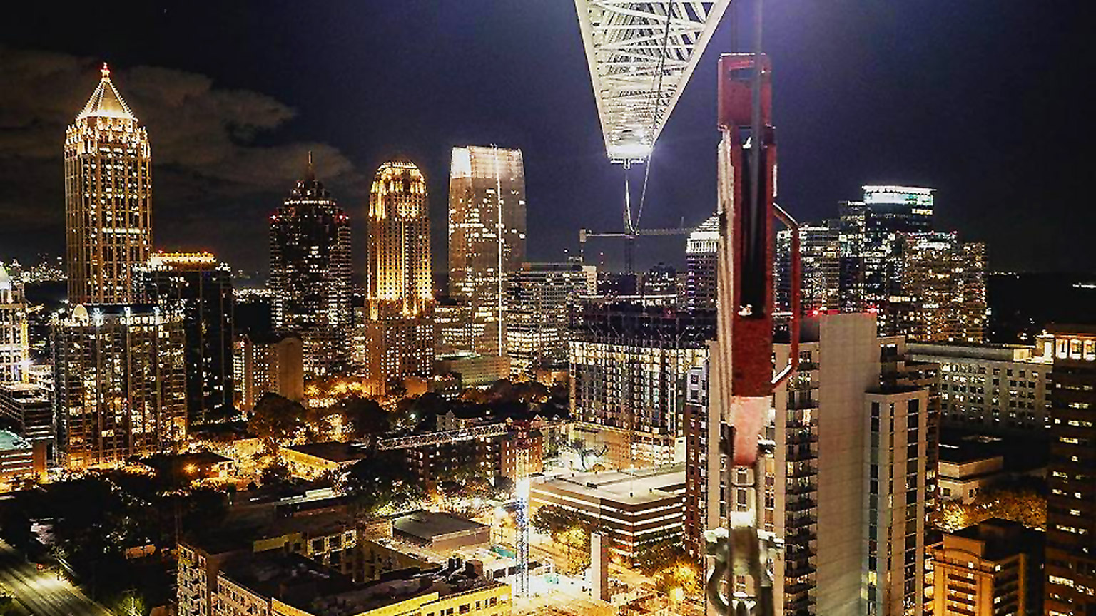 A construction crane overlooks a lit up Midtown Atlanta.
