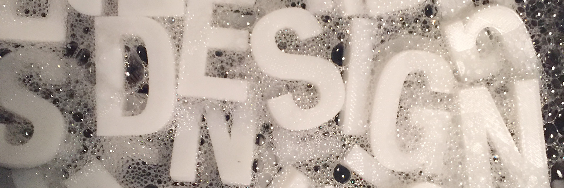 3D printed letters in a curing bath that spell "Design"