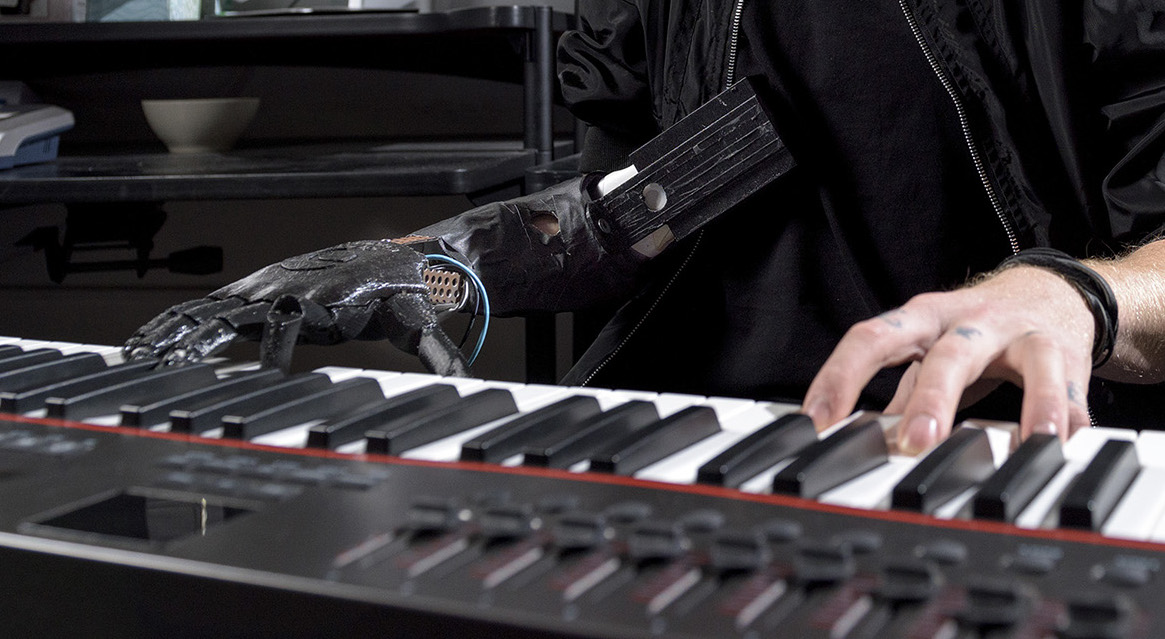 a man playing piano with a robotic prosthetic arm