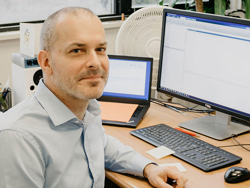 Alexander Lerch sitting at a desk with computer monitors in the background