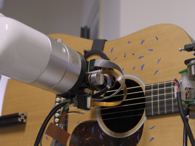 Robot arm strums acoustic guitar