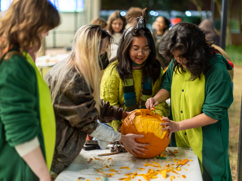 Students in costume carving a pumpkin