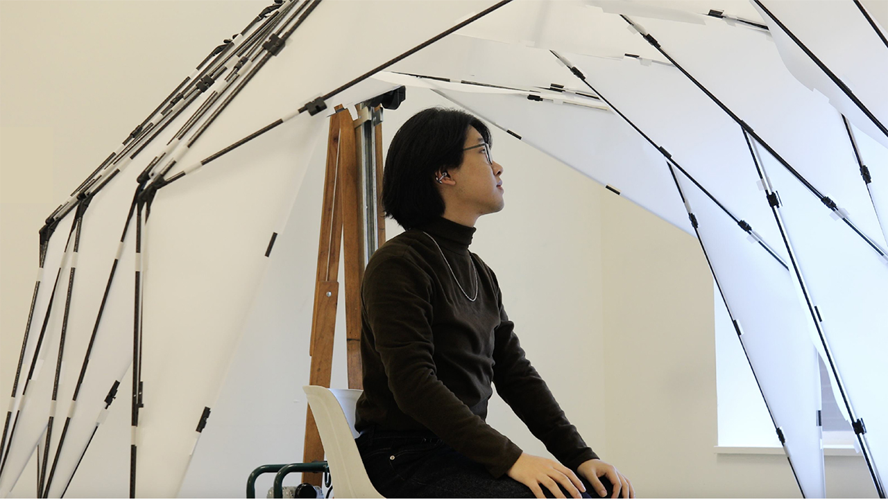A student sits inside a robotic canopy.
