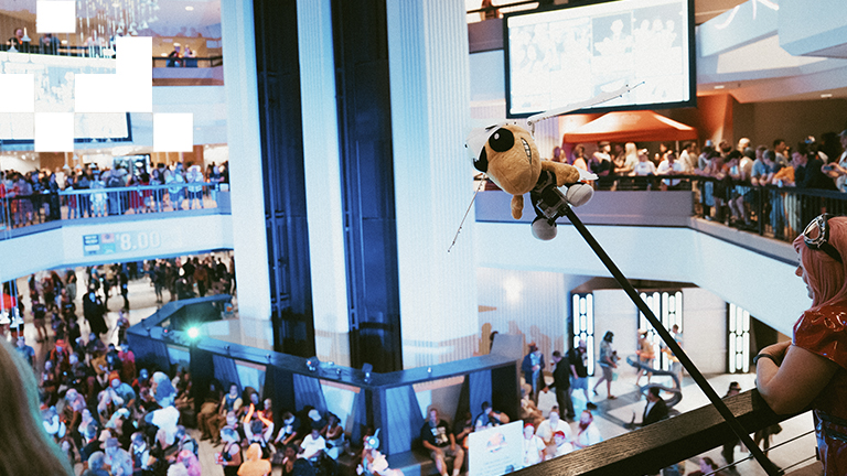 The Hilton Atlanta atrium with dancing Dragon Con attendees on several floors, and industrial design student project 'Bionic BuzzRa' overlooking the crowd.